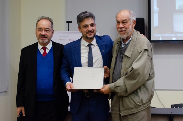 Vinicius Farias Campos recebe o diploma das mãos dos Acadêmicos Jorge Guimarães e Ruben Oliven (Foto: Rochele Zandavalli/UFRGS)